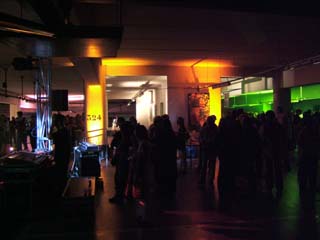 Dark parking garage with colored lights in background and silouettes of people in the foreground.