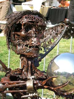 forged sculpture of an angle of death (in rusted iron) holding a mirrored sphere.