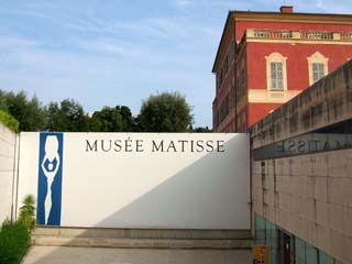 Matisse's villa in Nice with annex and large sign "Matisse" and image of "femme a l'amphore" (woman with amphora) which is a blue field defining the sillouette of a woman holding an amphora on her head.