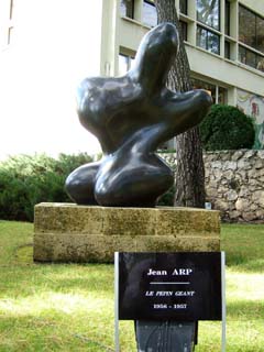 A sensuous abstract form in dark polished bronze can be viewed as a figure sitting on its knees.