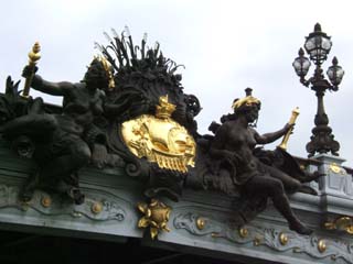 Close up view of two classical sculptures decorating the center span of the bridge.  Even the lamp post is heavily decorated.
