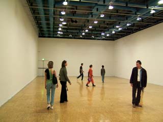 several people navigating in a n empty room stand orthogonal to each other.