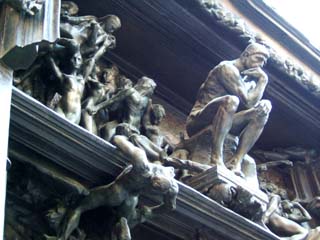 A close up of Rodin's sculptural depiction of Dante's "Gates of Hell".  Several human figures are suffering or falling while an image of Dante as the thinker presides over them.