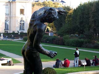 A view of several students drawing the rear facade of the Rodin museum are framed by a bronze figure in the foreground.