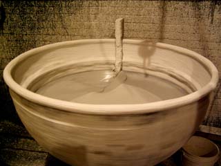 Image of large "dip" tank full of silicon polymer for building up the ceramic shell around the wax original.  Image shows tank in motion to keep polymer from solidifying when not being used.