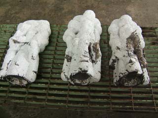 Ceramic shell molds are filled with dark metal.  Some cooled splashes of metal are also visible on parts of the molds.