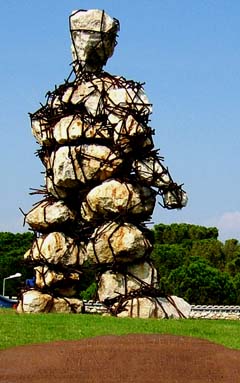 twenty foot tall sculpture of broken boulders bound by rebar