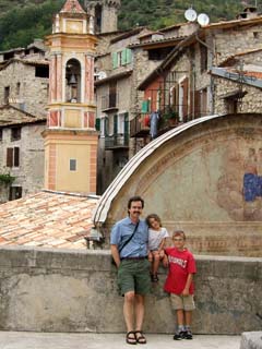 Me and my two kids at the edge of a terrace that overlooks the town of Luceram.