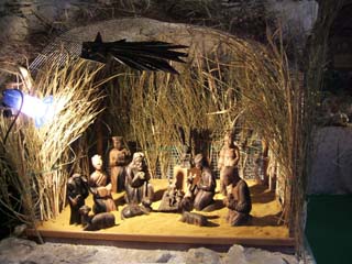 A set of carved wooden figures sit in front of a grass enclosure.