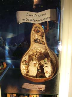 image of a gourd cut open to provide a setting for a nativity scene.  Several little figures made from seeds stand on various surfaces.