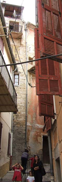 My family on one of the many narrow streets of Luceram.  The six story rock buildings with windows and shutters all the way up are only ten feet apart in this photo.