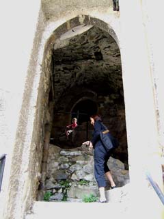 Maite and Aidan ascending a narrow stairway through a dark passage under row of buildings.