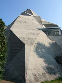 A large faceted model of a mountain nearly envelops the pavilian building.  Only one corner of the original structure is visible.