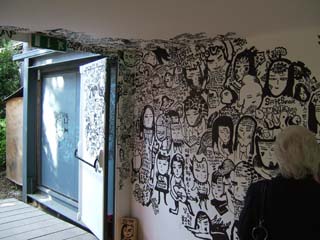 Hand drawn ink-on-building graffiti is made up of innumerable charcatures that one might expect to see on a highschool student's notebook line the walls, door and even outside the exit.