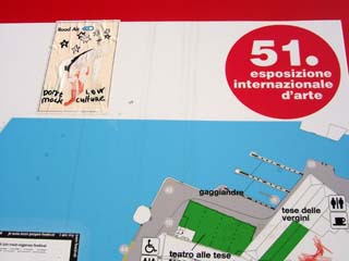 An enameled sign post for the Venice biennial shows the locations of exhibits, wheel chair access and toilets.  Pasted onto the sign are various stckers protesting the elitest nature of the Biennial.  One states "Don't Mock Low Culture".