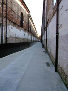 Long narrow walkway between brick buildings presents a single vanishing point.