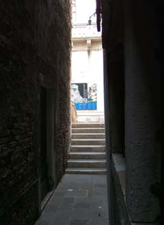 View Down a narrow walkway and over small bridge towards a sign declaring that this is a museum.