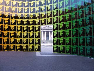 the inside of a large cylinder is lined with an array of over a hundred identical images of the Mona Lisa.  The only way out is through a doorway that looks out across the Grand Canal towards a classical Portico.