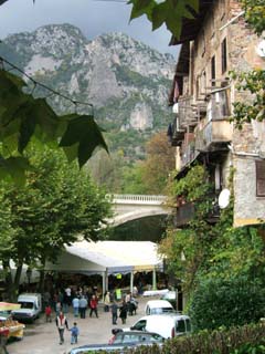 Image shows a tent pavillion in front of the main bridge in town.  Mountains rise fast in the background.