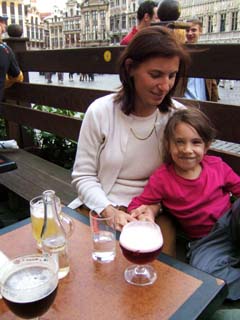 A little girls smiles for the camera while sitting in her mother's lap