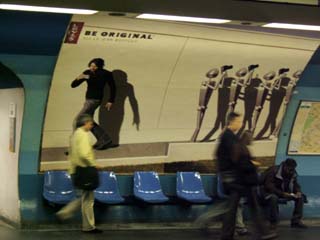 One of the typical "billboards" posted in the Metro advertises Levis Jeans (in English).  The billboard displays four nearly identical metal robots taking pictures in the same direction while a young man (in Jeans) walks in a different direction but is also taking a picture.