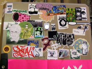 A utility p[anel is covered with stickers with images that look like graffitti and in some cases advertise websites of graffitti writers.